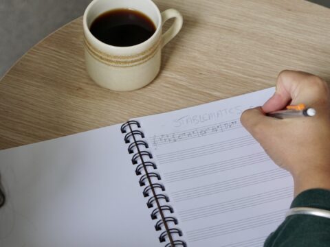 A music manuscript notebook with jazz chords being written in it.